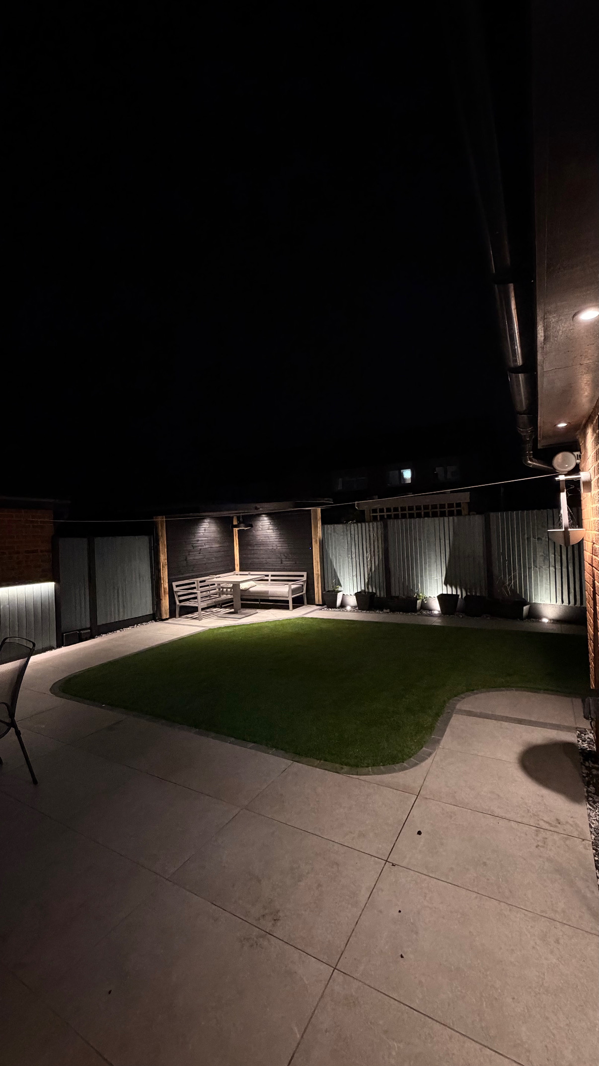 Garden seating area with eave downlights and recessed wall lighting at night